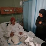 Sanaa Khalil, 35, a Syrian farmer who lost her two legs in the past days by an Israeli airstrike while she was working at a banana plantation, lies on a bed as she is assisted by a relative at a hospital in the southern port city of Tyre, Lebanon, Friday, May 1, 2026. (AP Photo/Hussein Malla)