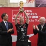 Prime Minister Mark Carney raises the FIFA World Cup trophy during a trophy tour event at Lansdowne Park's Aberdeen Pavilion, as FIFA President Gianni Infantino, right, and Italian soccer legend Alessandro Nesta, left, look on in Ottawa on Sunday, May 24, 2026. THE CANADIAN PRESS/Justin Tang