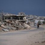 A Palestinian man rides his bicycle by the rubble of buildings that were destroyed during the Israel Hamas war, in Khan Younis, southern Gaza Strip, Friday, July 31, 2026. (AP Photo/Abdel Kareem Hana)