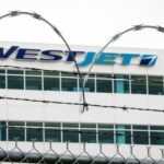 The WestJet headquarters building is seen through razor wire as WestJet flight attendants hold a "Day of Action" while union members vote on a possible strike in Calgary, Tuesday, July 14, 2026. THE CANADIAN PRESS/Jeff McIntosh